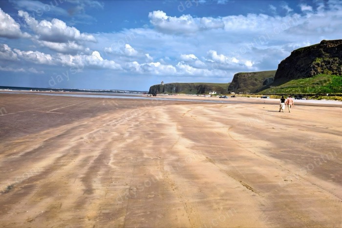Wide golden sand at Benone Strand with cliffs rising in the distance