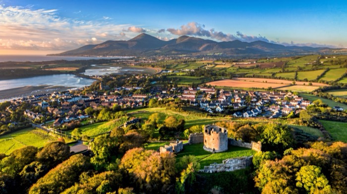 Aerial view of Dundrum Castle on its hilltop with the Mourne Mountains behind