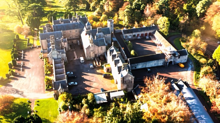 Aerial view of the Gothic Parkanaur Manor surrounded by autumn woodland