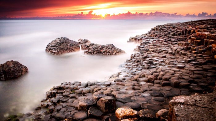 The basalt columns of the Giant's Causeway glowing under a fiery sunset