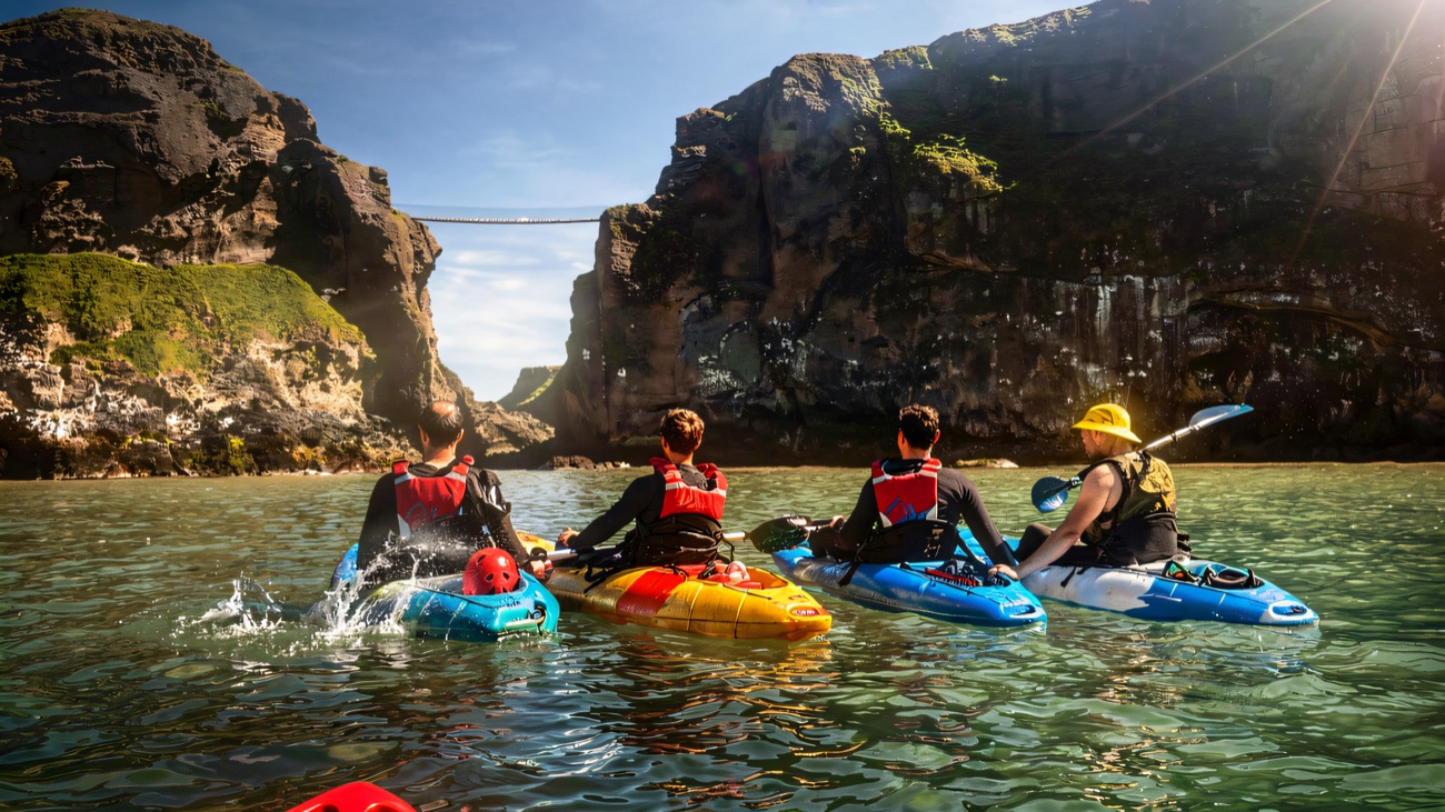 Kayaks slipping toward a hidden sea arch on turquoise water