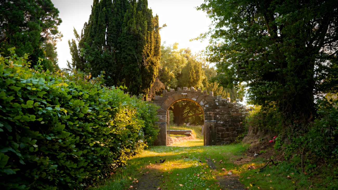 The stone archway gateway at the end of the grassy lane leading up to the graveyard