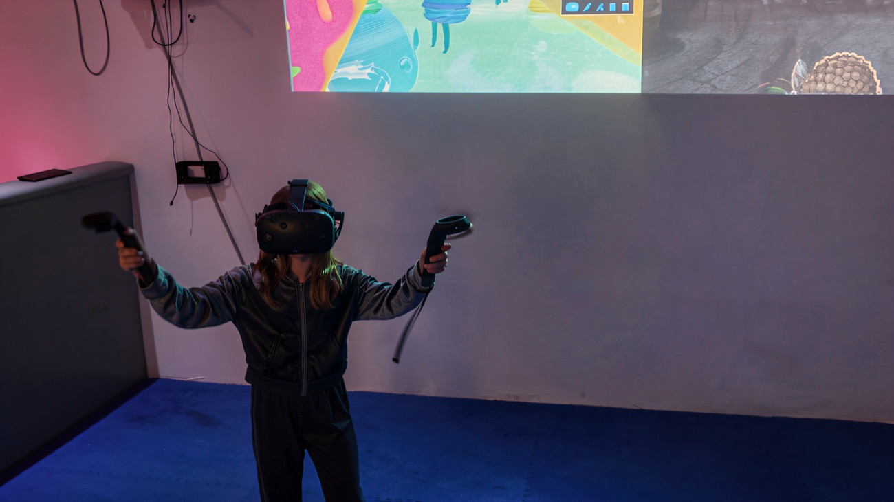 A player in a VR headset mid-game on the arcade's blue-lit floor