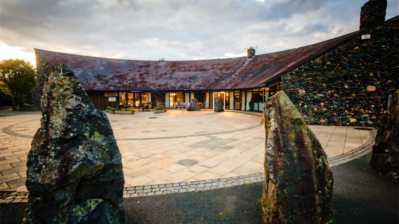The circular flagged forecourt framed by upright stones, echoing the ancient monuments nearby.