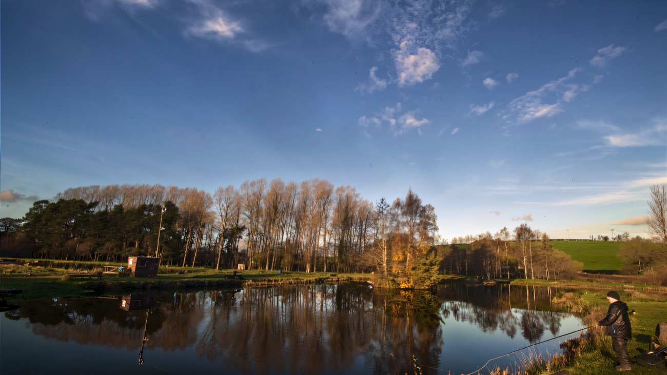 Anglers spaced along the bank under a wide blue sky