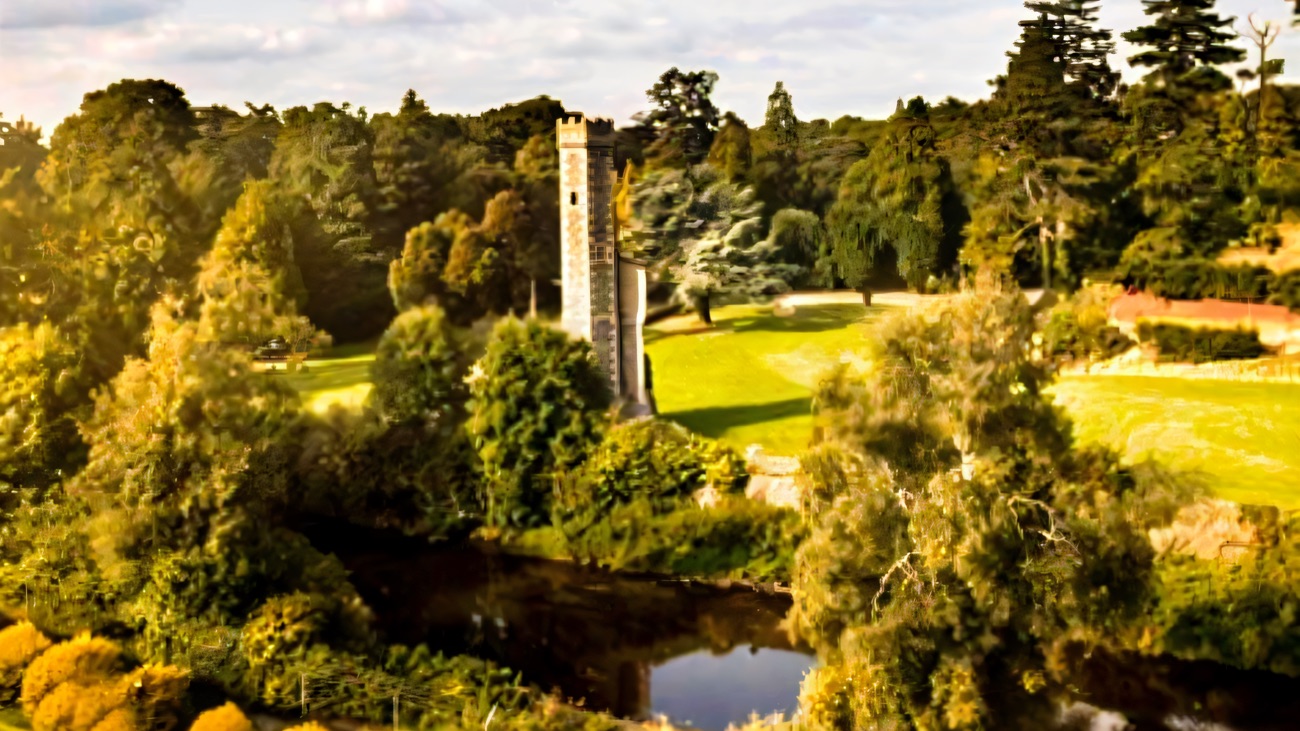 The old round tower on the mound above the river, set among lawns and trees in the grounds