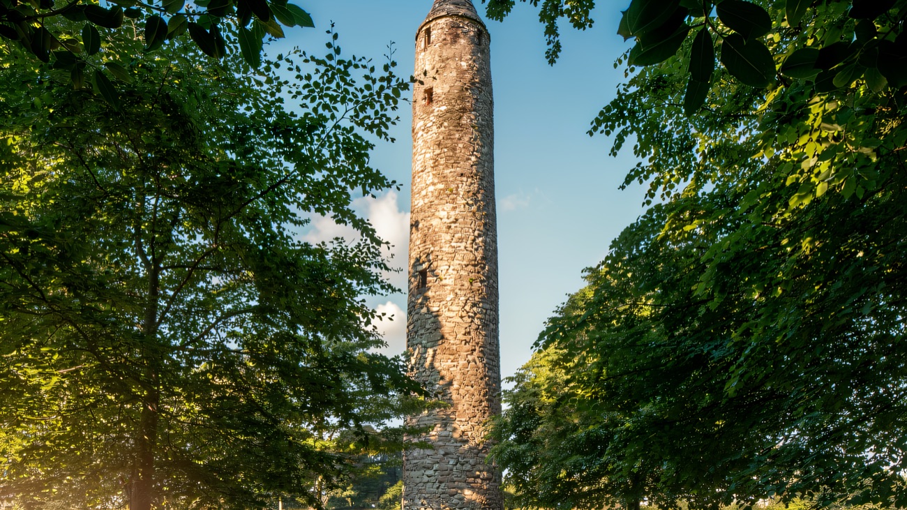 A glimpse of the weathered stonework through a screen of green summer foliage