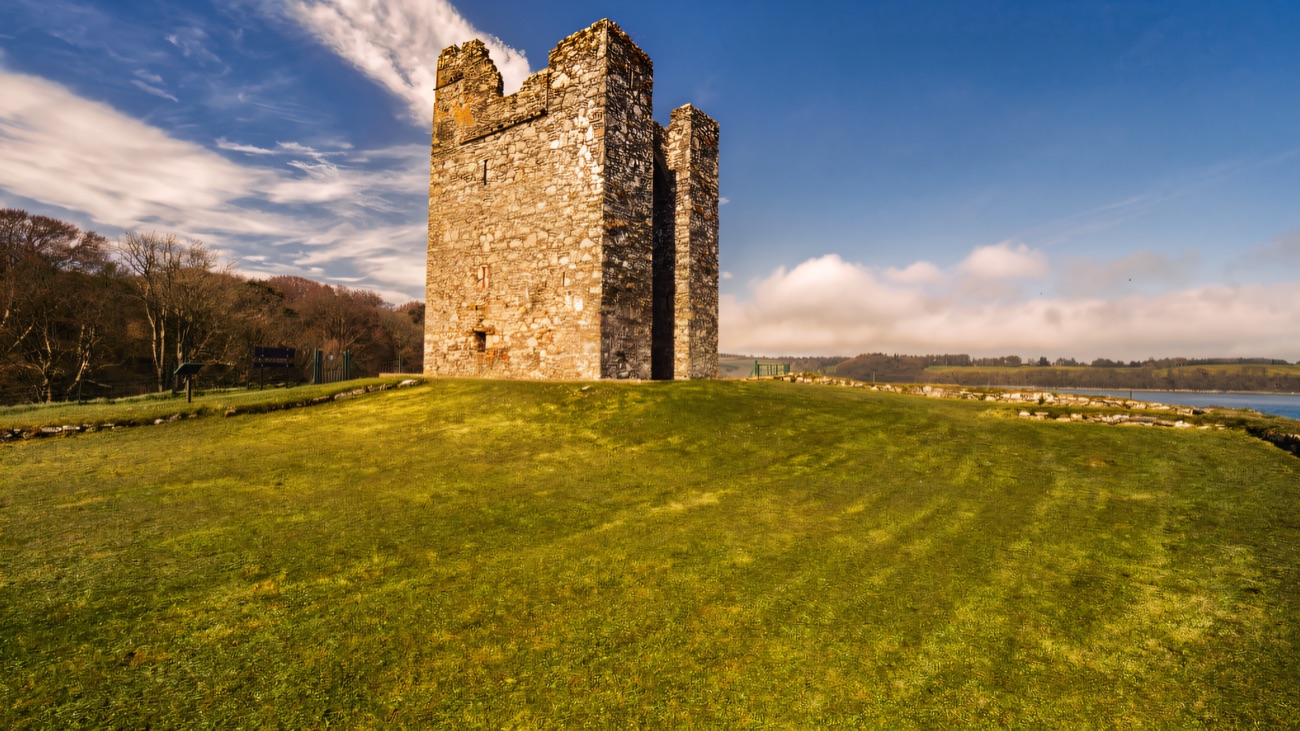 The castle crowning its grassy knoll with the lough shining behind