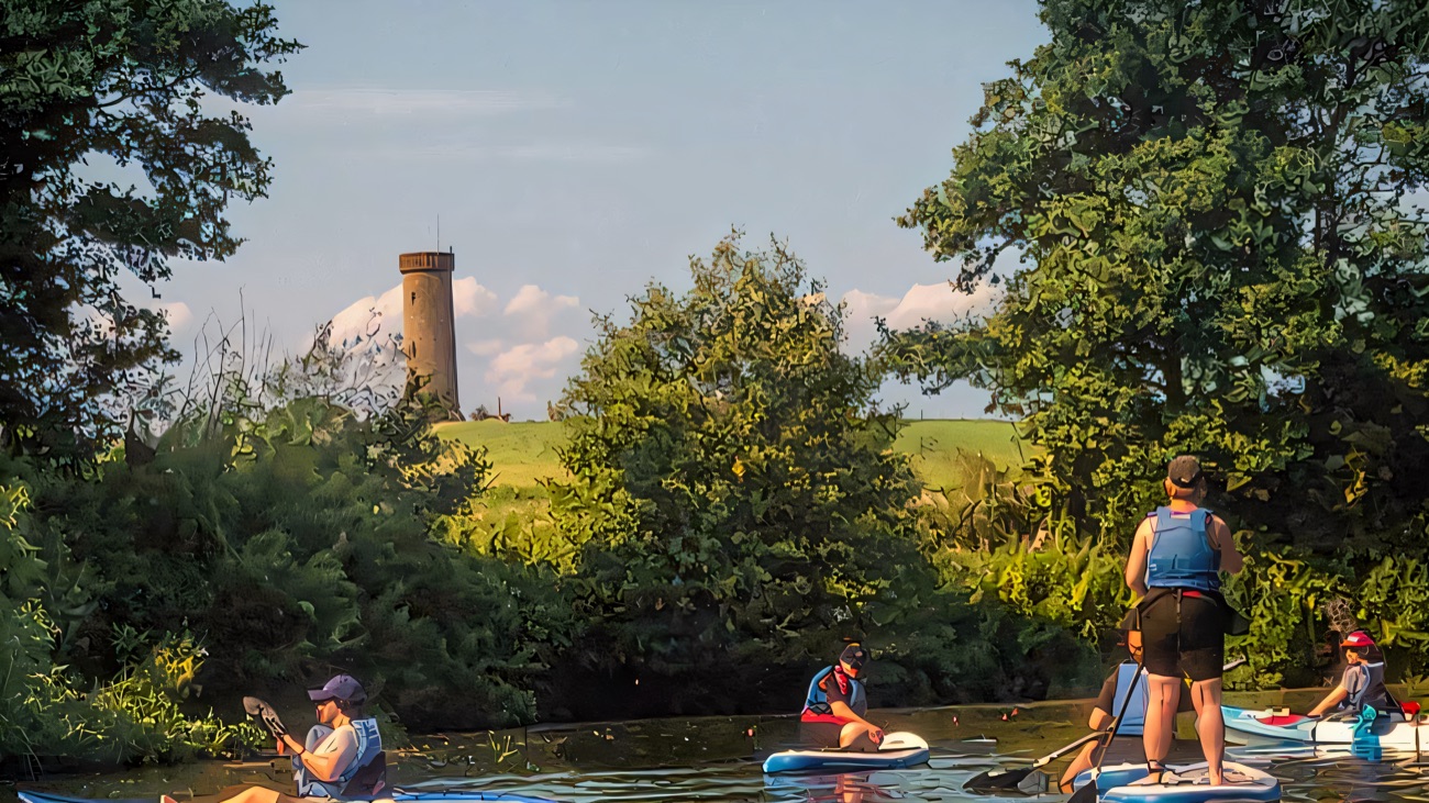 Paddleboards and kayaks drifting the river below an old hilltop tower