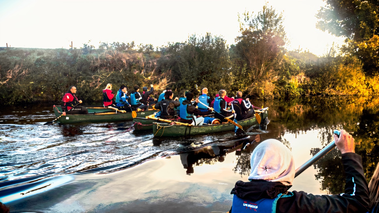 A convoy of canoes glides down the calm, tree-lined Blackwater