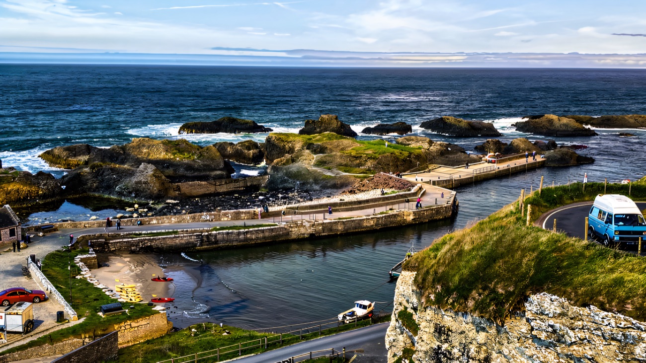 Ballintoy Harbour from the hill above, with kayaks on the slipway and rocky islets offshore