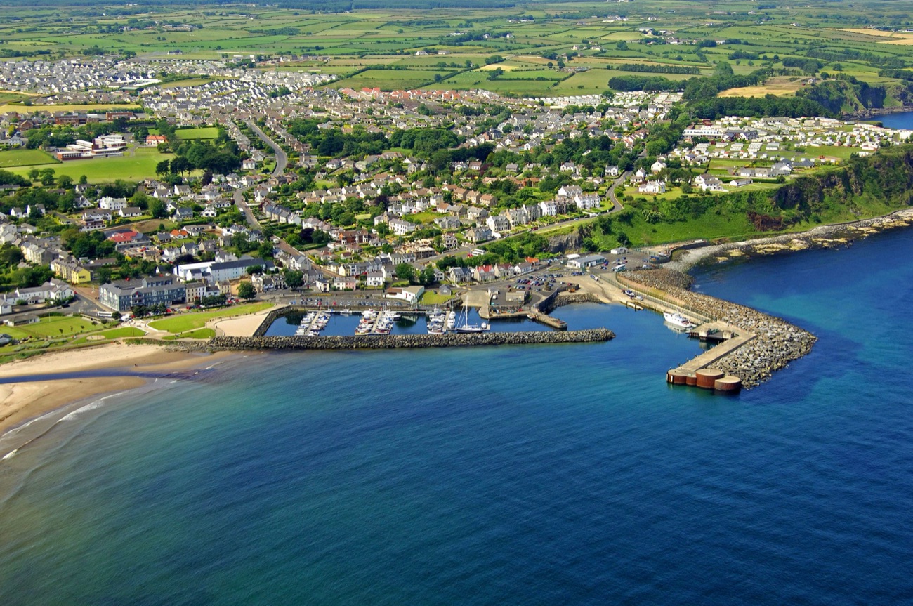 Aerial view of Ballycastle harbour and marina with the beach curving away and the town behind