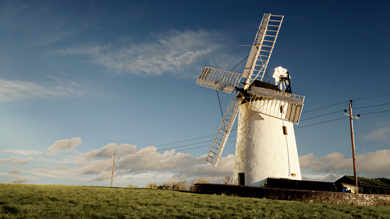 The whitewashed tower mill standing above the fields near Millisle, its sails and fantail turned to the wind.