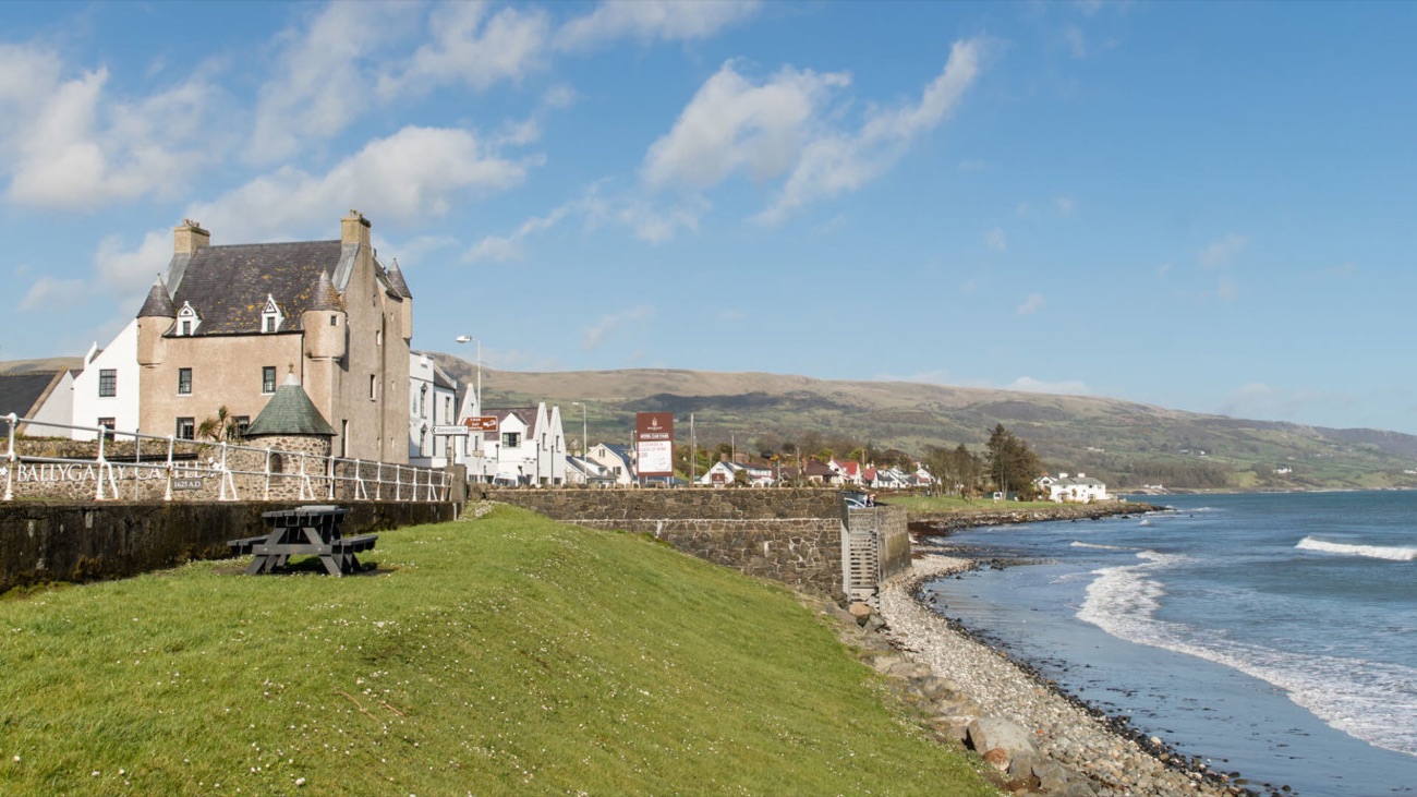 Ballygally Castle standing over the seafront with the sweep of the bay and the Antrim coast beyond