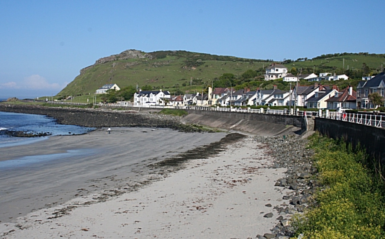 The sandy beach and sea wall at Ballygally with the village terrace and headland behind