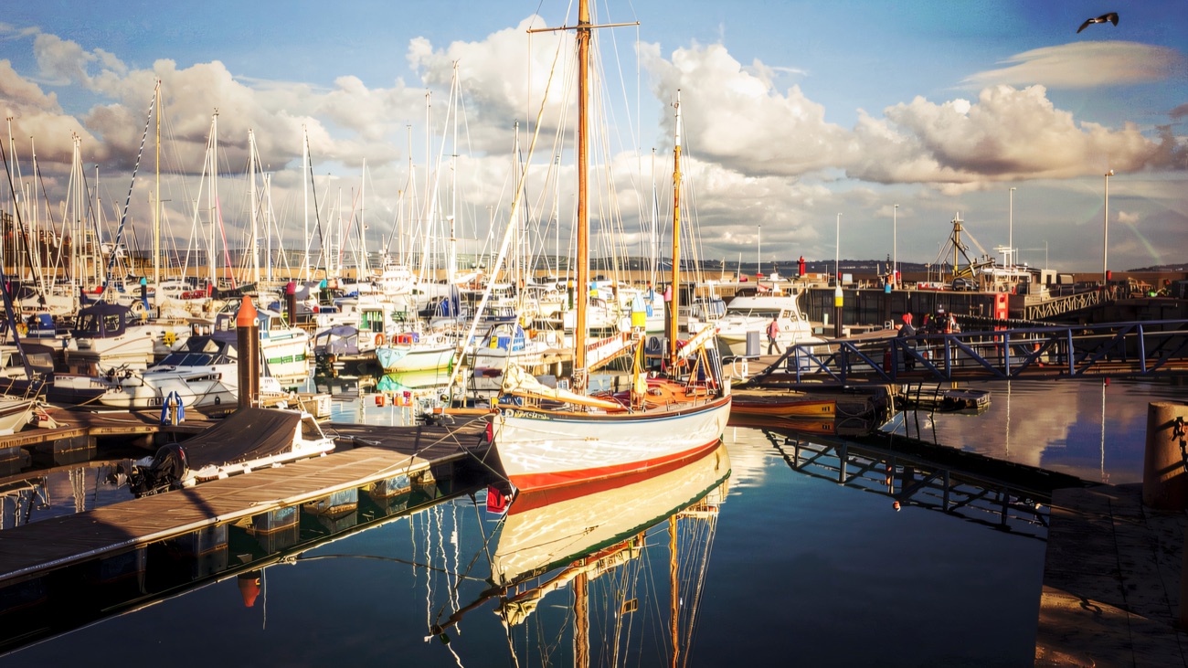 A classic wooden boat mirrored in the still marina water