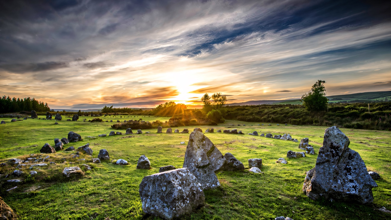 The stone circles and cairns spread across open moorland, caught in low evening light.
