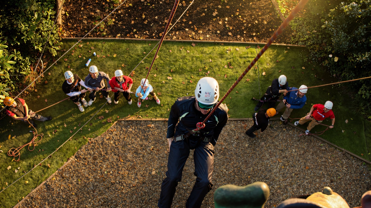 Looking down on a helmeted climber abseiling the tower wall