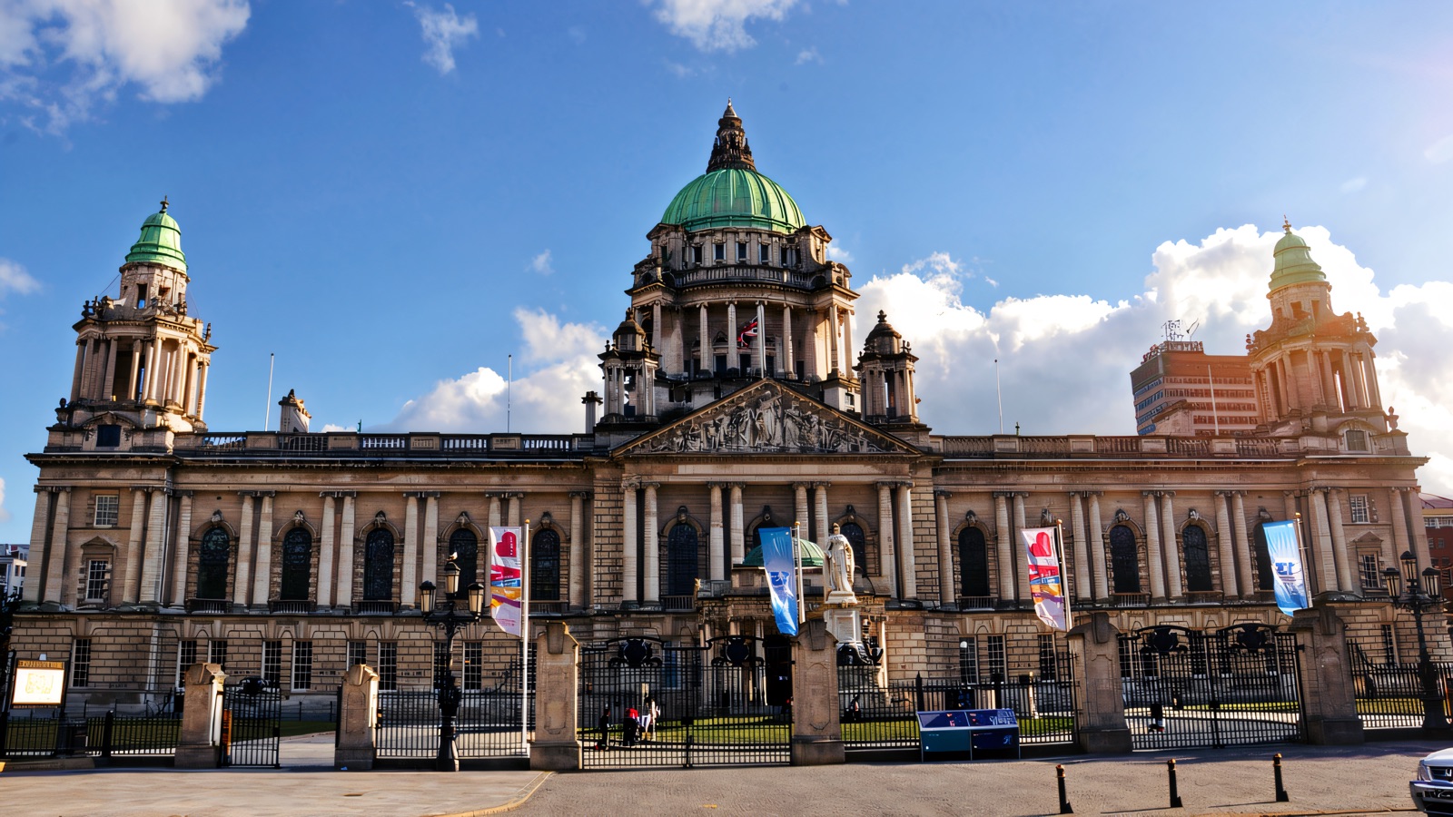 The grand front facade of Belfast City Hall in Portland stone with its green copper domes against a blue sky