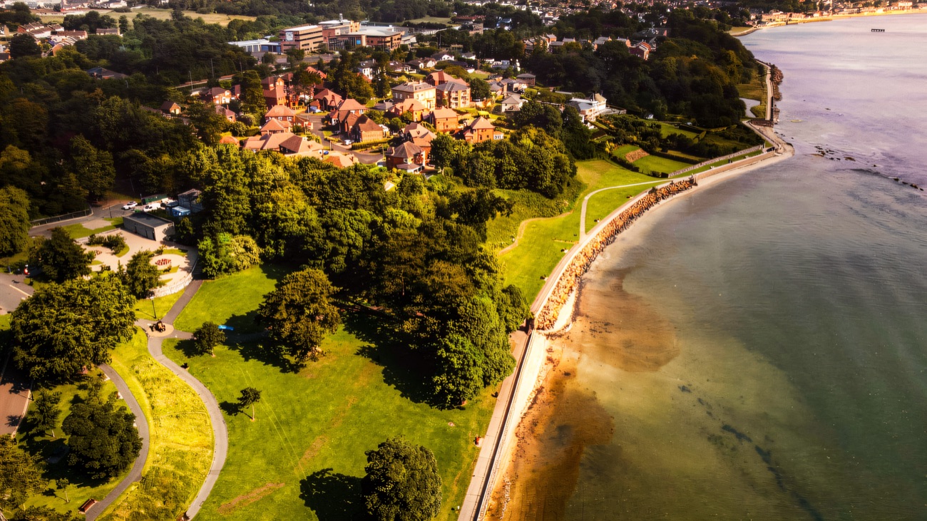 An aerial of the shoreline path curving along Belfast Lough