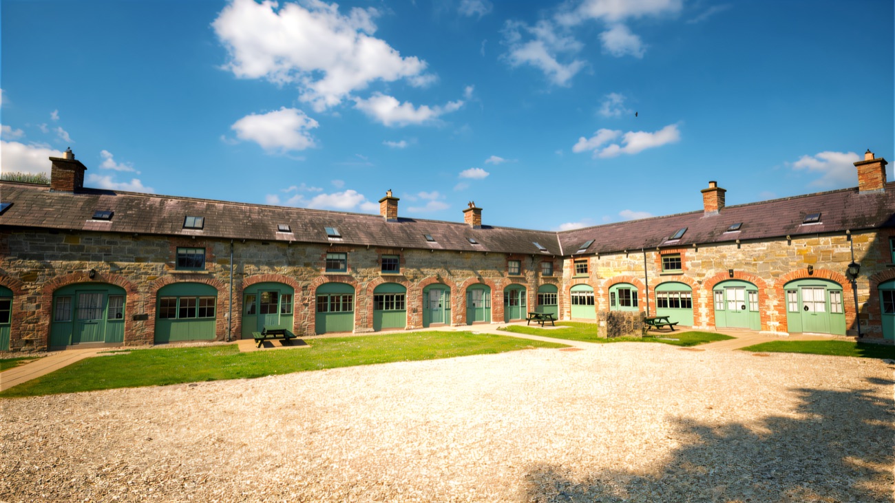 The estate courtyard of stone cottages with green-painted arched doors and picnic tables