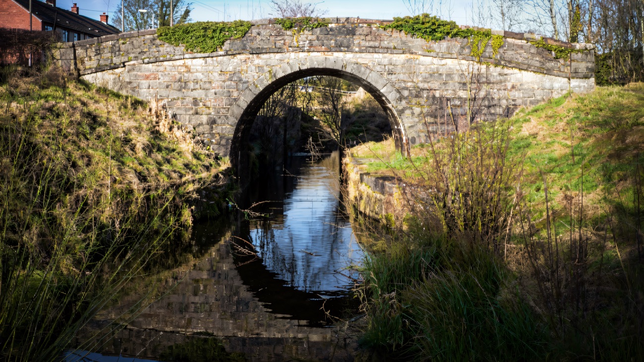 A stone hump-back bridge over the restored Ulster Canal at Benburb, its arch reflected in the still water