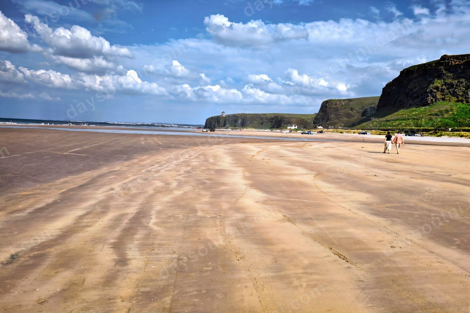 The vast open firm sand of Benone Strand stretching to the Binevenagh cliffs and Mussenden Temple in the distance under a big blue sky