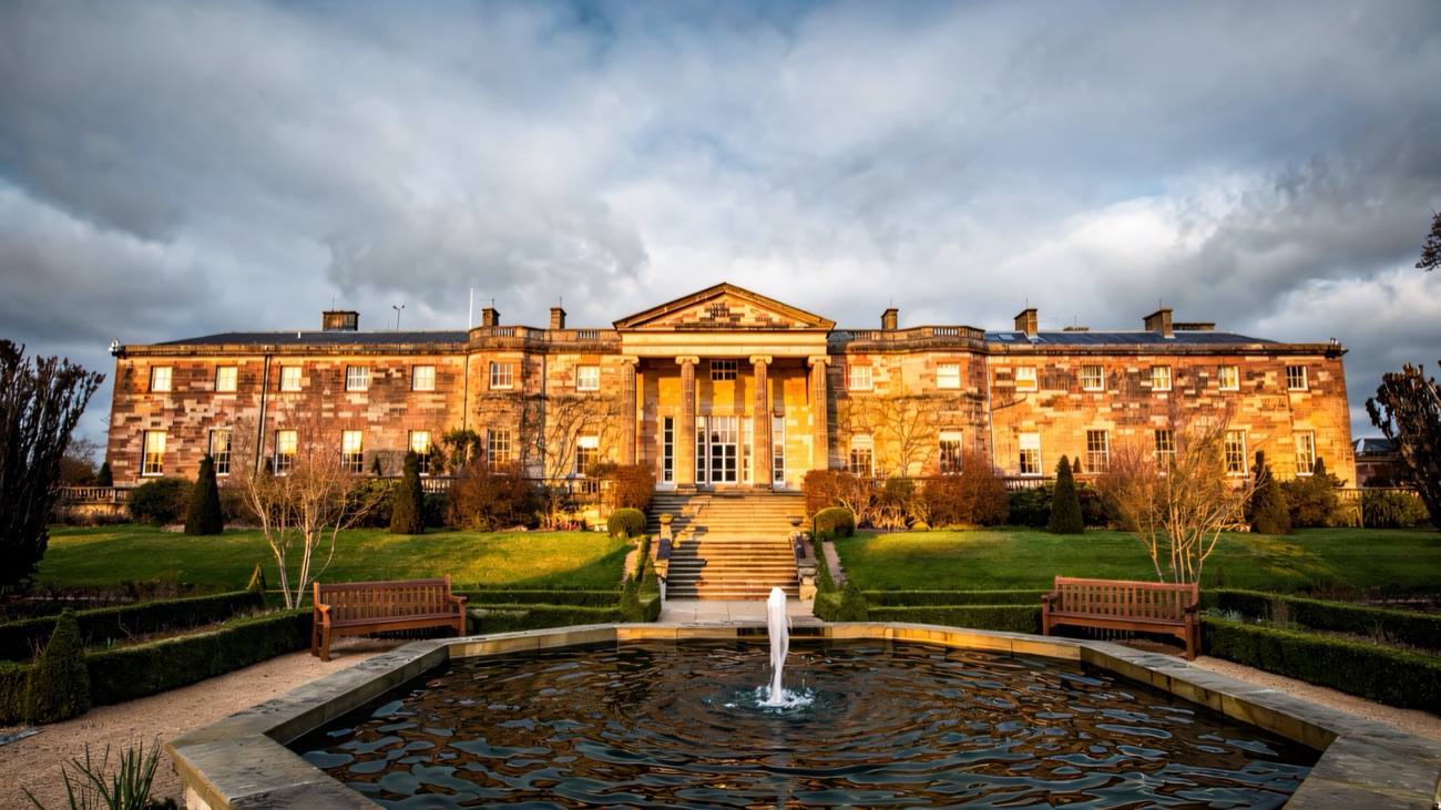 The Georgian front of Hillsborough Castle glowing in evening light behind the fountain pond