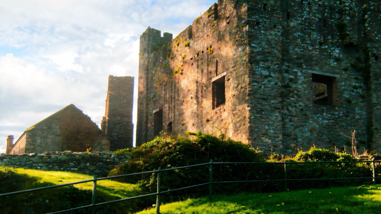 The stone keep and ruined walls of Greencastle Royal Castle catching low golden light near Kilkeel