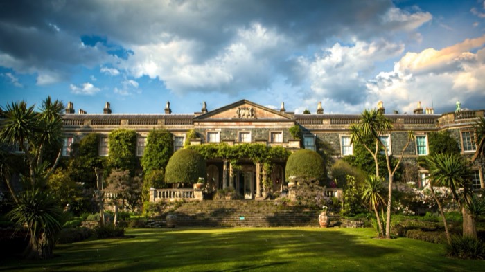 The grand front of Mount Stewart house behind its lawns and palms