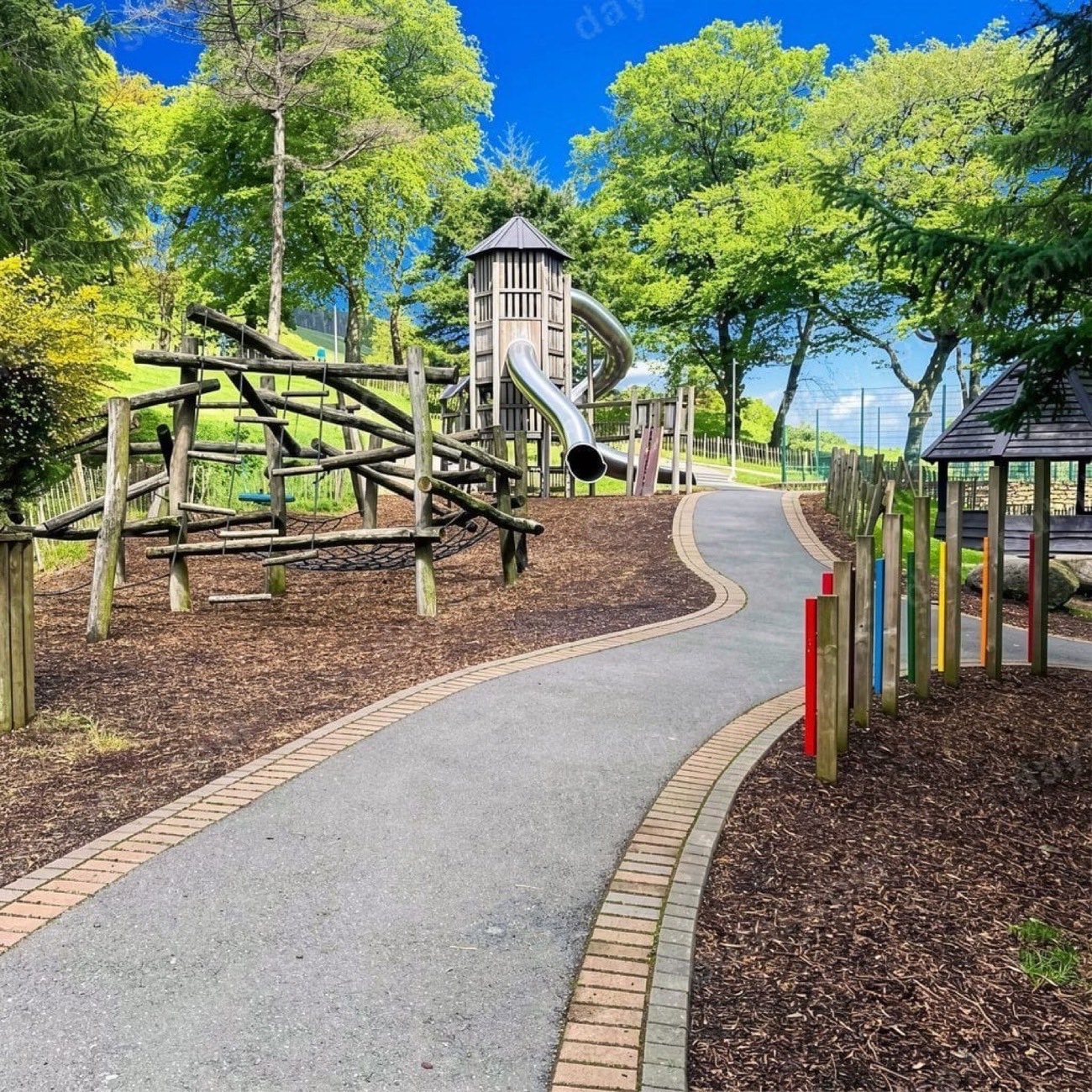 Wooden climbing frame and tower slide beside a winding path at the Slieve Gullion adventure playpark