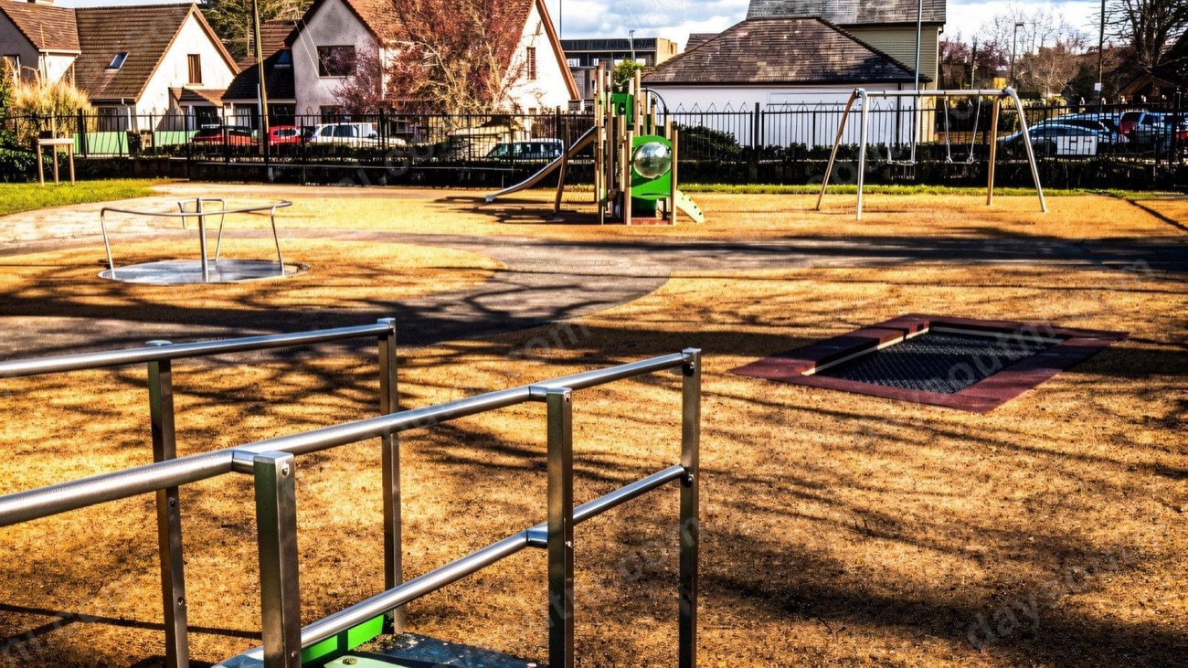 Swings, a roundabout and an in-ground trampoline in low sunshine at The Playtrail in Eglinton