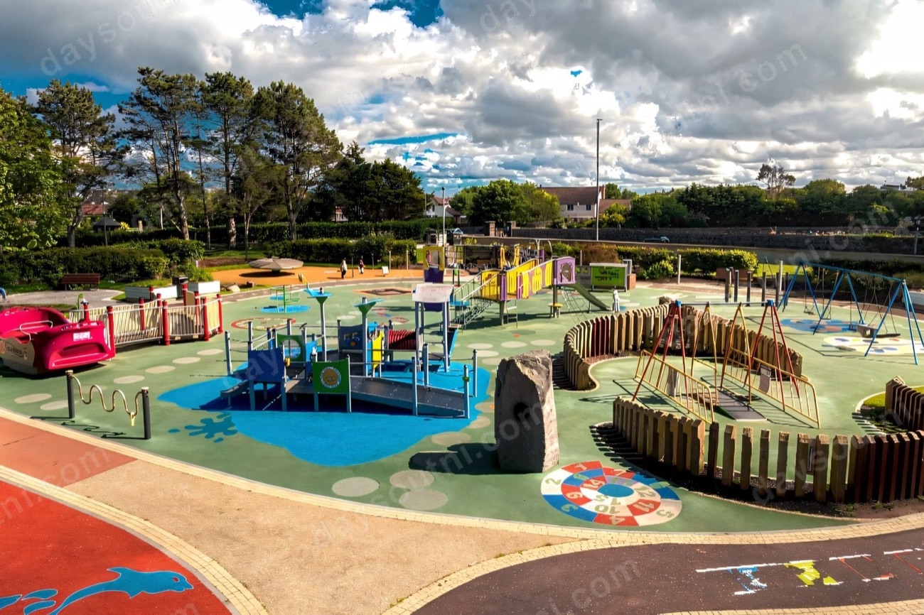 Wide view of the colourful accessible playground at Flowerfield Park in Portstewart under a big summer sky