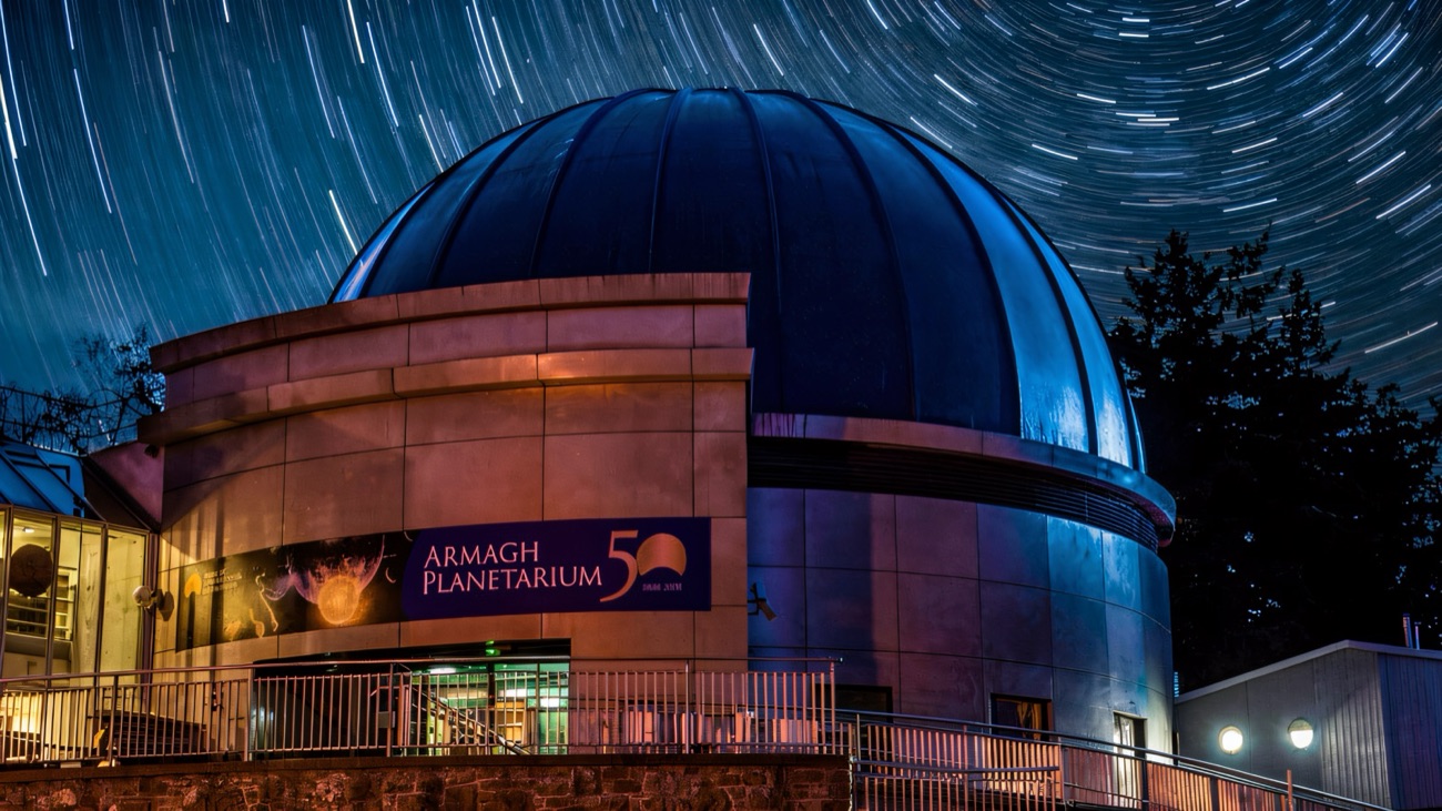 The dark dome of Armagh Planetarium at night beneath swirling star trails