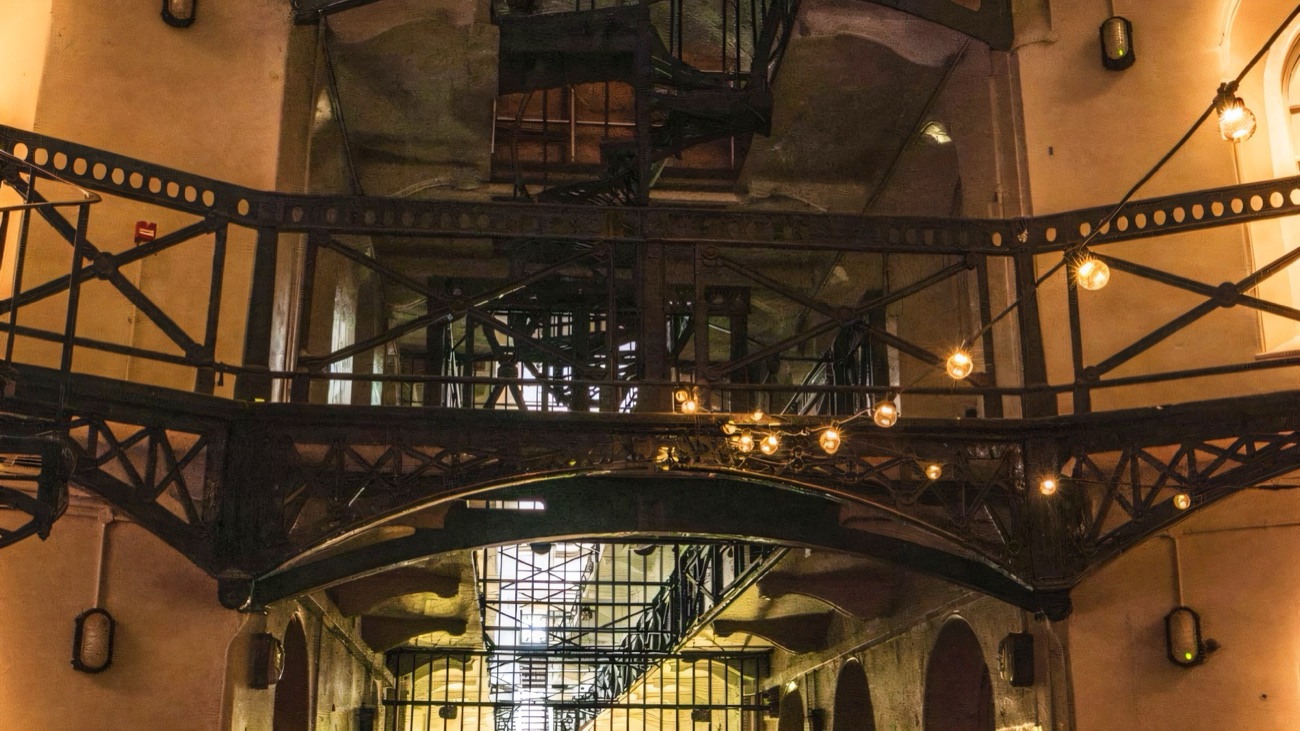 Iron bridges and spiral stairs criss-crossing the tall C-wing atrium of Crumlin Road Gaol