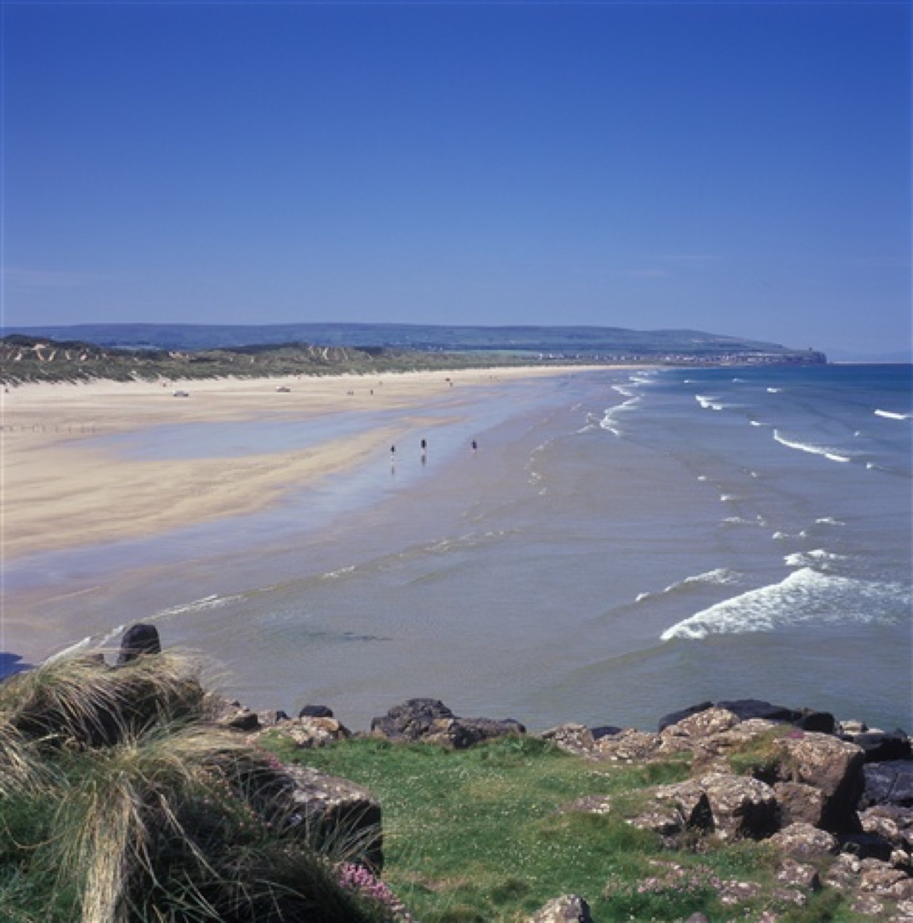 The rocky shore at the Portstewart end of the strand, looking along two miles of sand