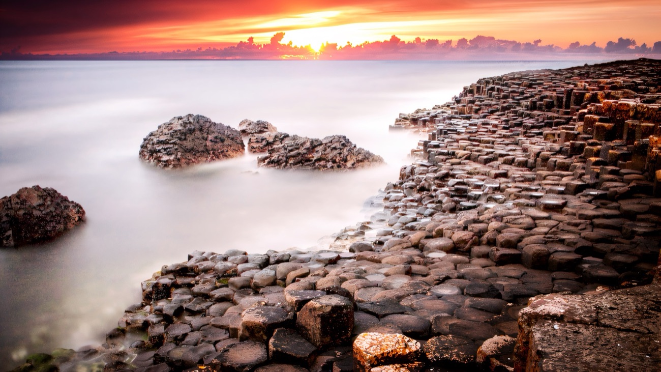 The basalt columns of the Giant's Causeway glowing under a fiery sunset
