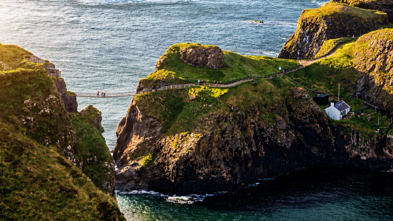 The Carrick-a-Rede rope bridge crossing a chasm to a rocky island in golden light