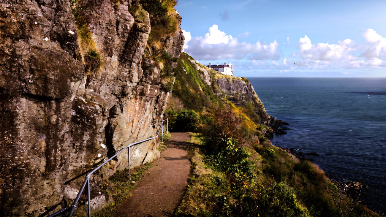 The cliff path cut into the rock, railing leading toward the lighthouse