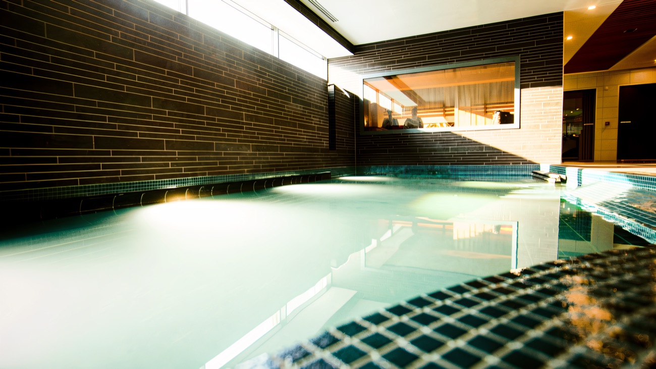 The indoor spa pool with the sauna cabin looking on behind glass