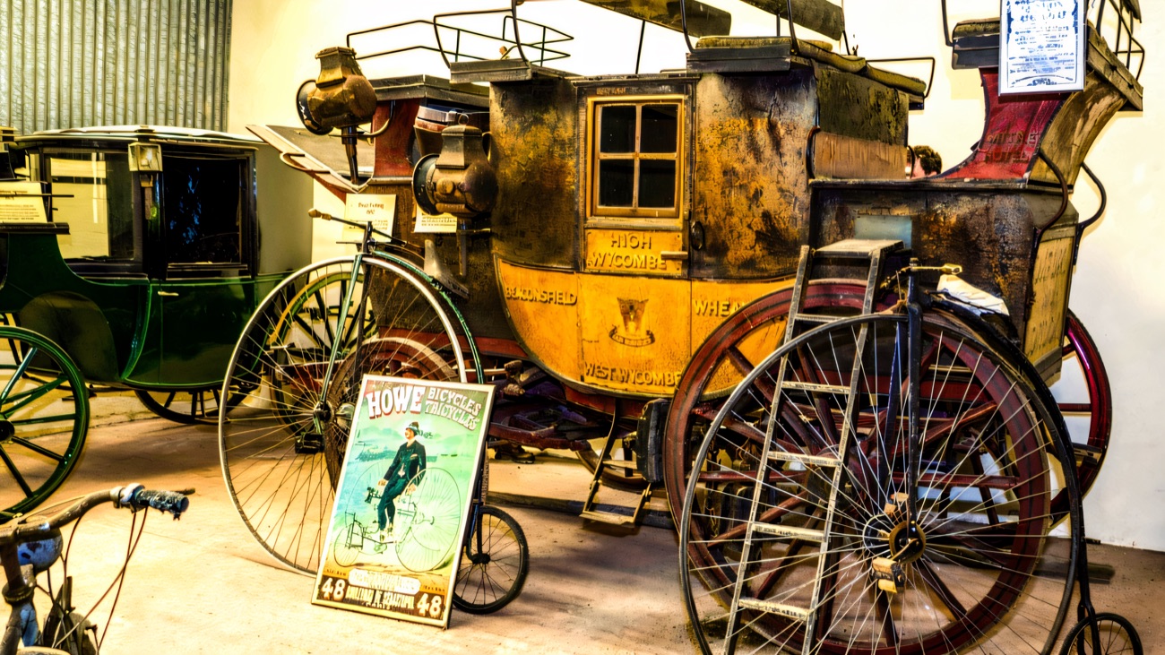 Old horse-drawn coaches and penny-farthing bicycles in the Carriage & Costume Museum