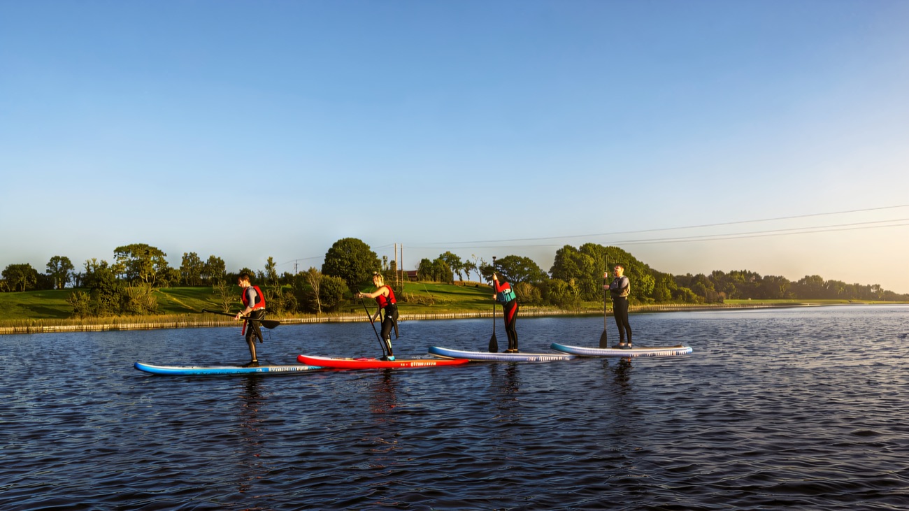 Four paddlers in a bright row across a mirror-calm Lough Erne evening