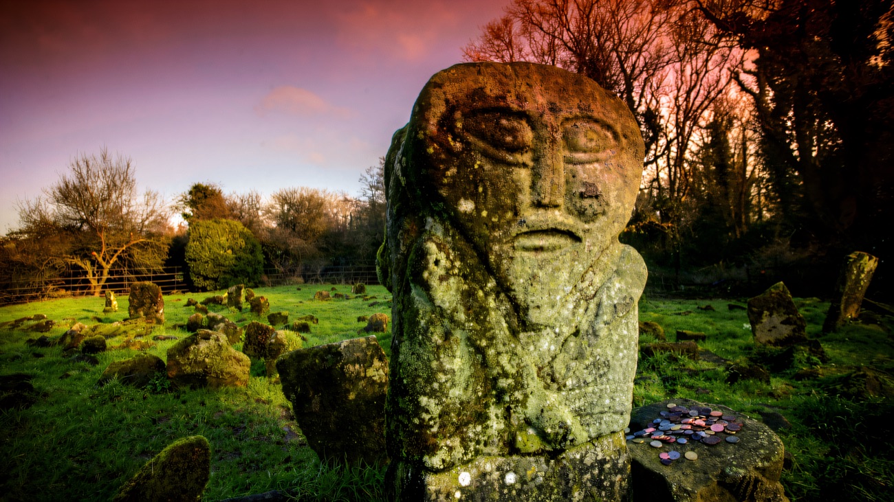 The two-faced Janus figure catching a magenta dusk in the old graveyard