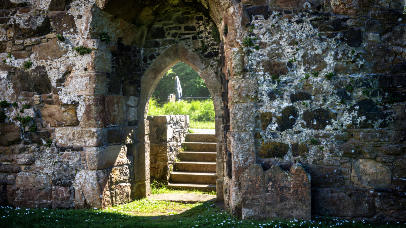 A pointed doorway and worn steps leading through the old stonework