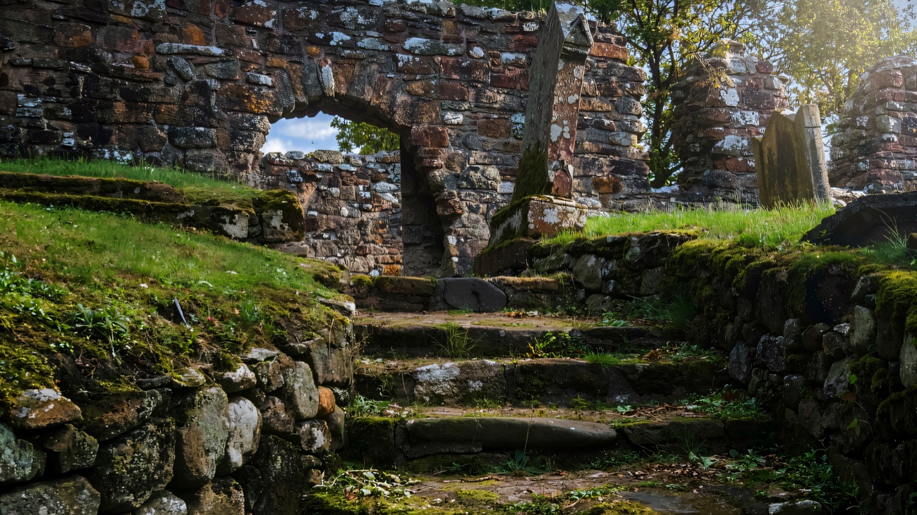 Worn stone steps climb to the arched doorway of the ruined medieval church in its hillside graveyard.