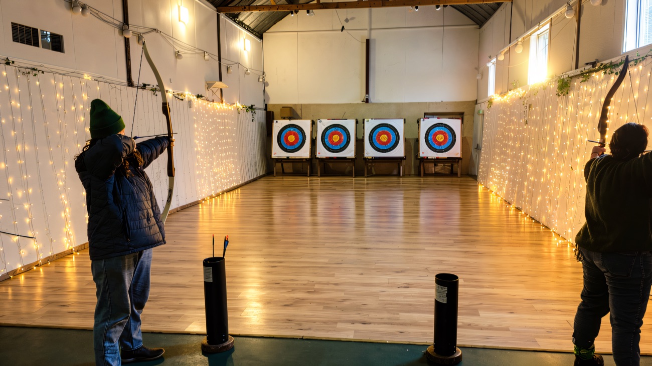 The indoor archery hall, bows drawn towards four target bosses
