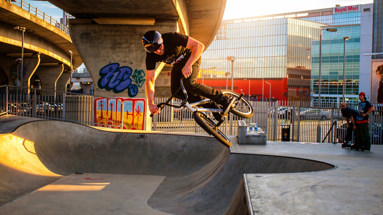 A rider catching air over the concrete bowl beneath the flyover