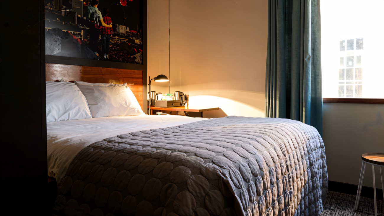 A bedroom with a printed artwork panel above the bed and a tea tray on the side table
