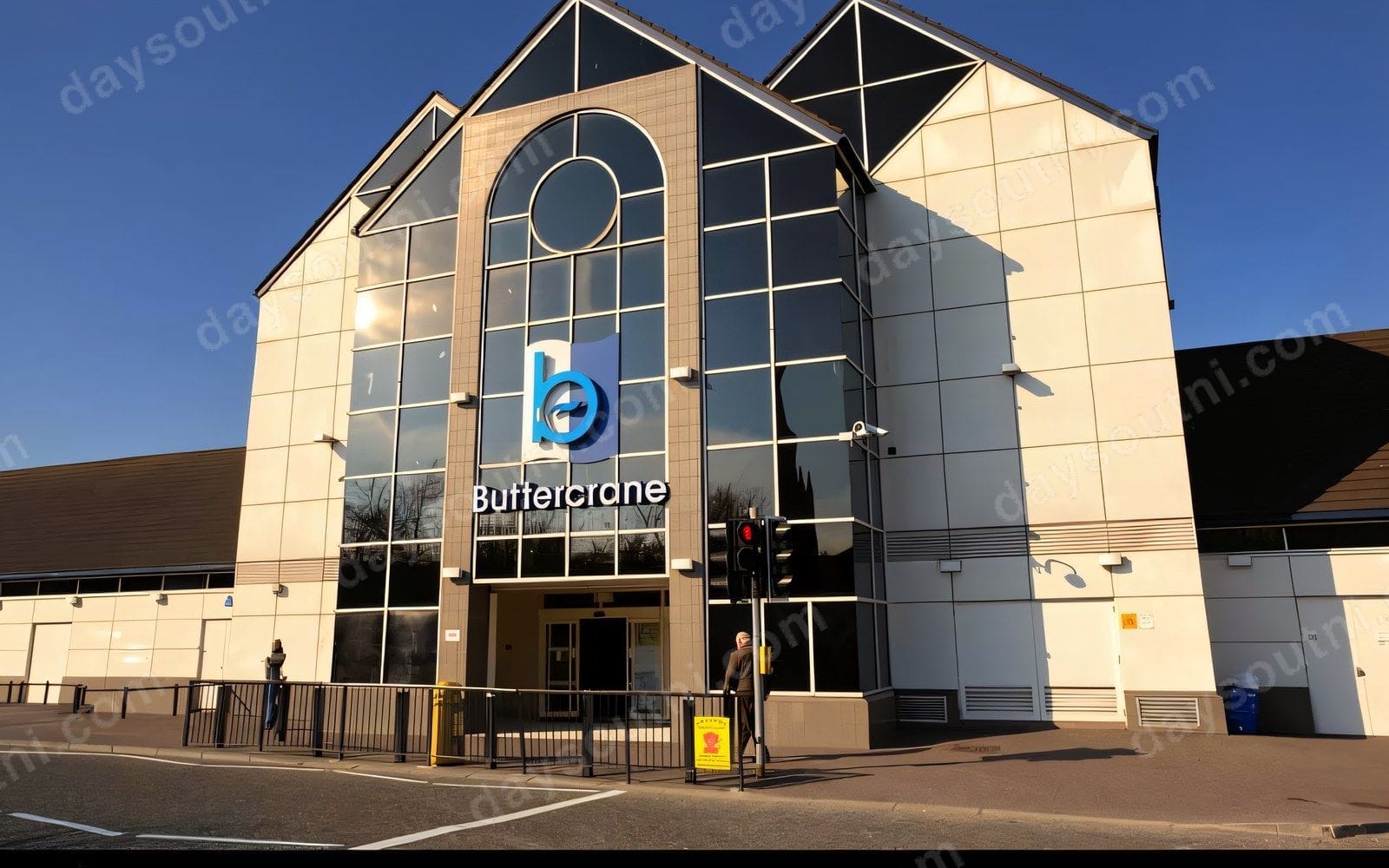 The glass-fronted main entrance of Buttercrane Shopping Centre on Buttercrane Quay, Newry, under a blue sky