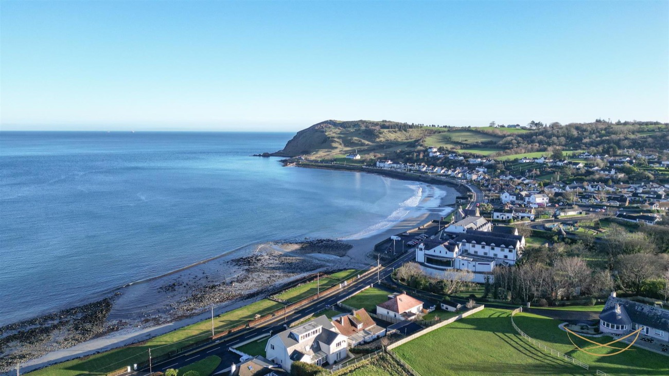 Green hills and headland above Ballygally sweeping down to a sandy bay on the Antrim coast
